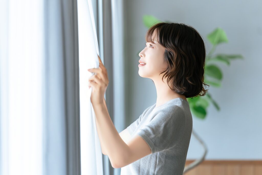 カーテンを開ける女性